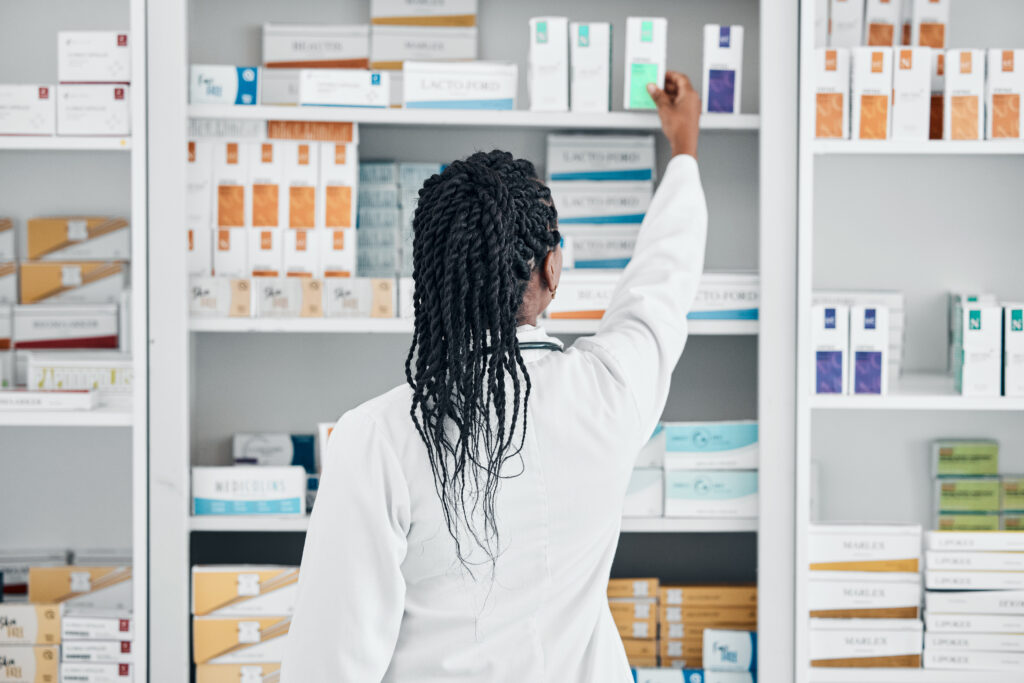 a pharmacy owner stocking shelves of medical supplies wondering if owning a pharmacy is still profitable