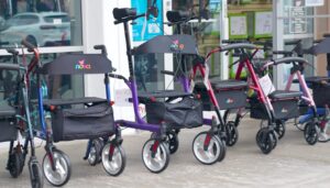 an assortment of colorful NOVA rollator walkers outside a store, in a range of heights, wheel sizes and build styles